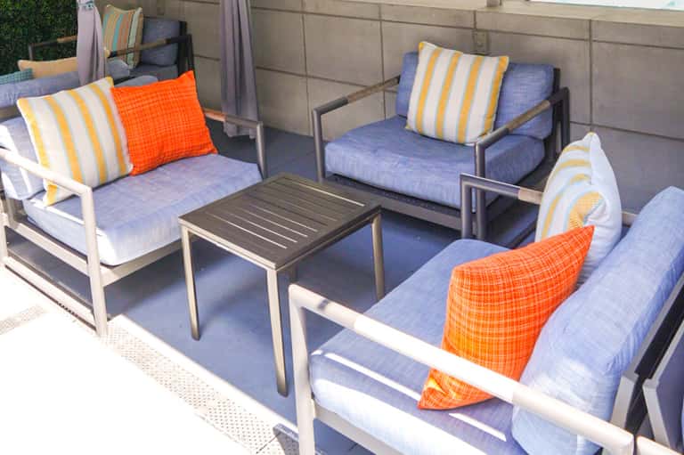 Outdoor patio seating area with blue cushioned chairs, striped pillows, and metal side table