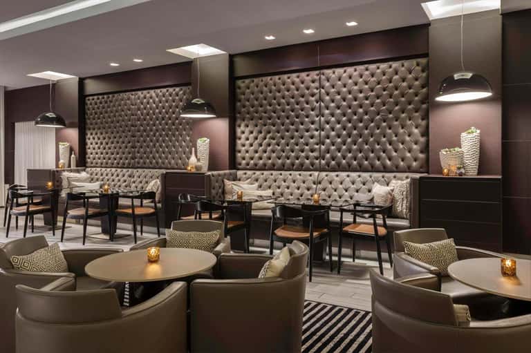 Elegant hotel lounge with tufted seating, pendant lighting, round tables, and modern interior design