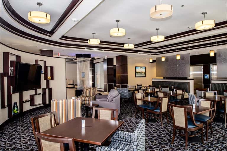 Upscale hotel lounge with elegant furnishings, curved ceiling with pendant lights, and dining area