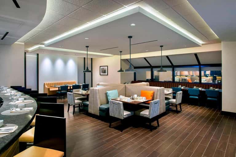 Modern restaurant interior with booth seating, pendant lighting, and ocean-view windows