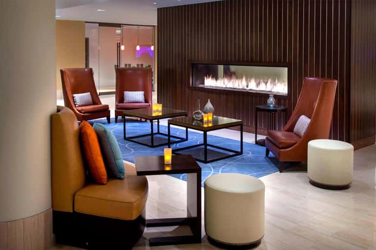 Modern lounge with rust-colored leather chairs, fireplace, blue patterned rug, and contemporary furnishings