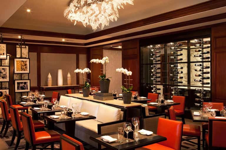 Upscale dining room with dark wood, red chairs, orchid centerpieces, and wine display cases