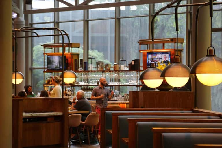 Modern café interior with hanging gold globe lights, wood accents, and large windows overlooking city