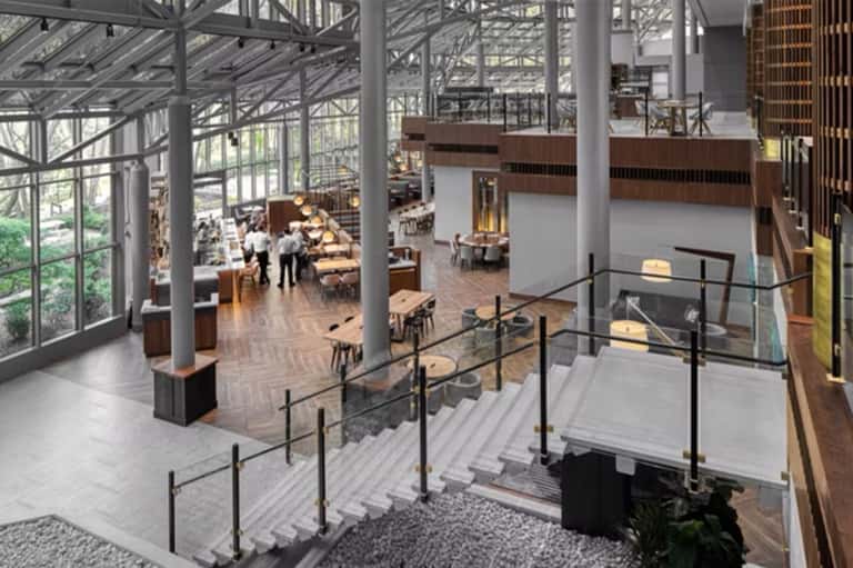 Modern multi-level dining hall with floor-to-ceiling windows and industrial ceiling beams