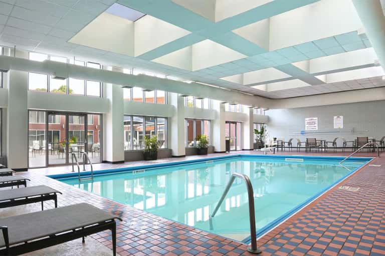 Indoor swimming pool with blue water, skylights, and lounge chairs in bright facility