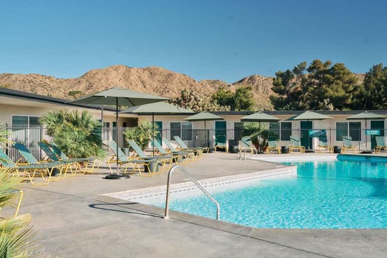 Resort pool with yellow loungers, desert mountains backdrop, and palm trees