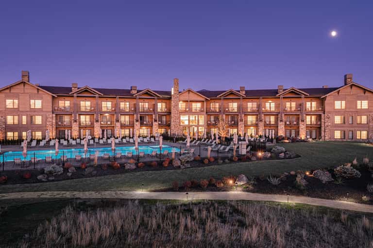 Brick residential buildings at twilight with illuminated windows, pool area, and manicured grounds