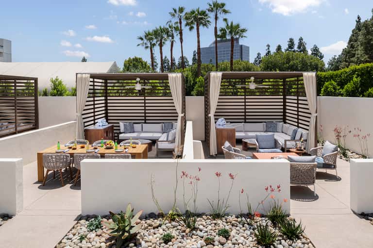 Modern rooftop terrace with lounge seating, dining area, and city skyline views