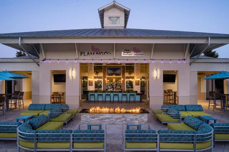 Flamingo's restaurant pavilion with fire pit, blue seating, and string lights at night