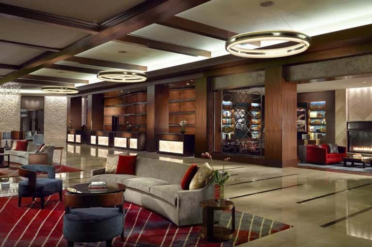 Luxury hotel lobby with dark wood paneling, modern circular pendant lights, and contemporary seating