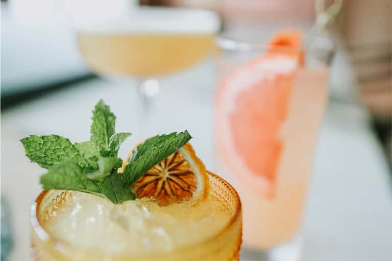 Craft cocktails with citrus garnish and fresh mint on a bar counter