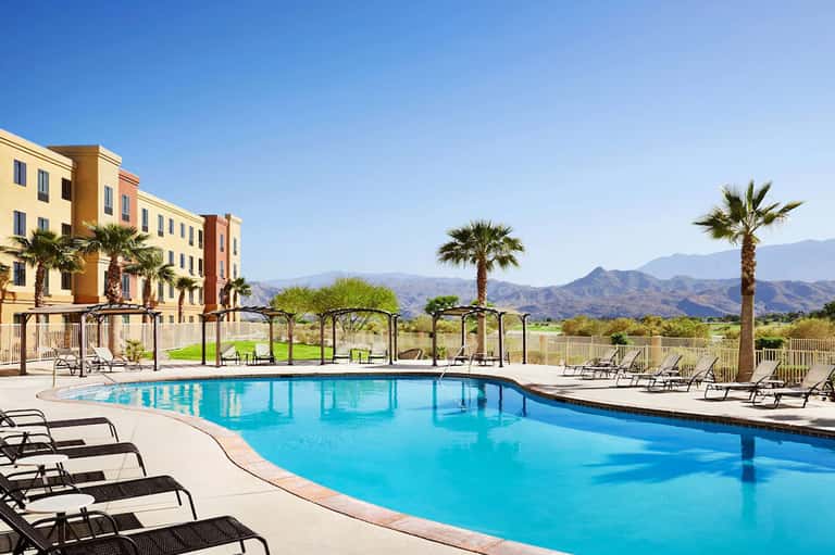 Hotel pool with mountain views, loungers, and desert landscape in background