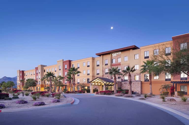 Colorful hotel exterior at dusk with palm trees and illuminated entrance