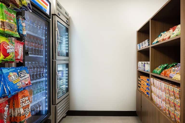 Hotel market convenience area with vending machines stocked with snacks and beverages on wooden shelves