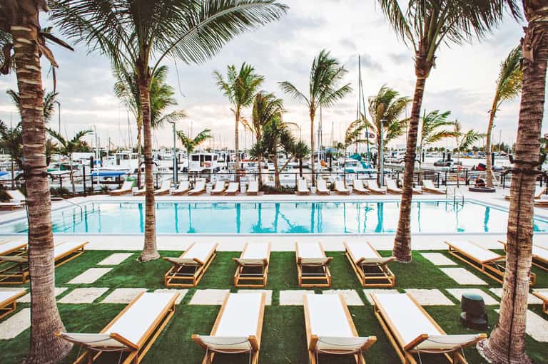 Marina pool surrounded by palm trees with sailboats docked in background