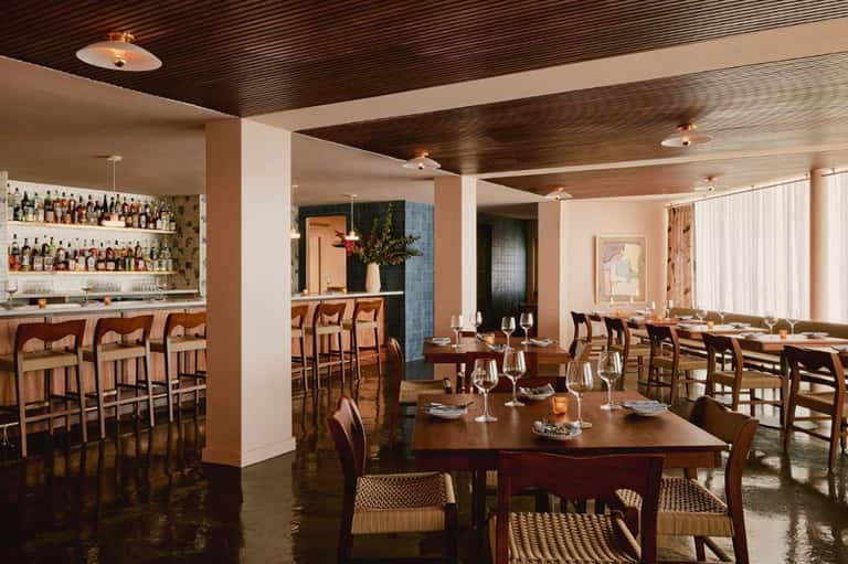 Upscale restaurant and bar with wood ceiling, dining tables, and extensive liquor collection behind counter
