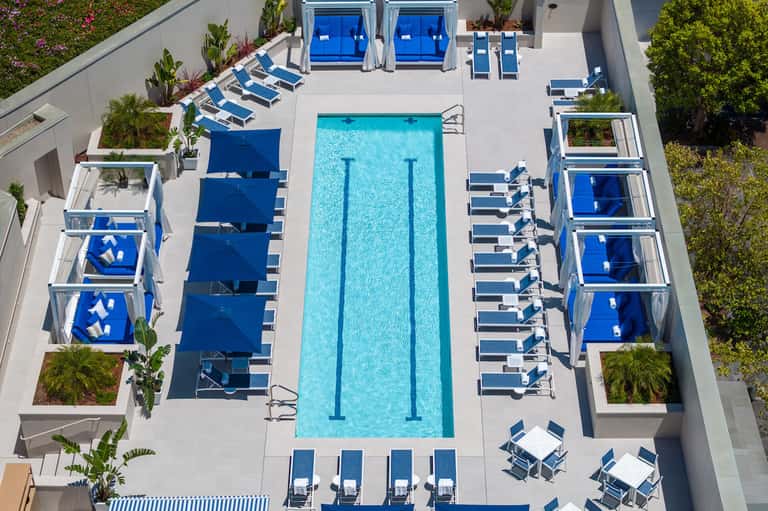 Aerial view of rectangular lap pool with blue umbrellas and lounge chairs on deck