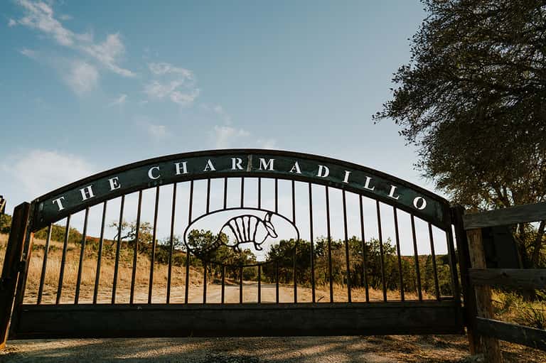 Black ornate gate entrance to The Charmadillo equestrian property with horse logo