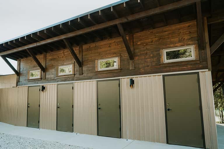 Modern wooden building exterior with multiple green doors and upper windows