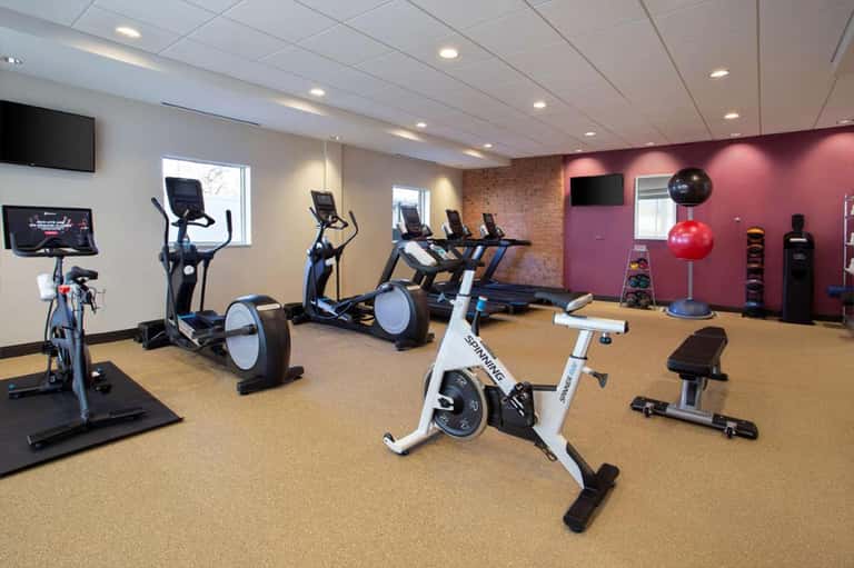 Modern fitness center with stationary bikes, ellipticals, treadmill, and pink accent wall