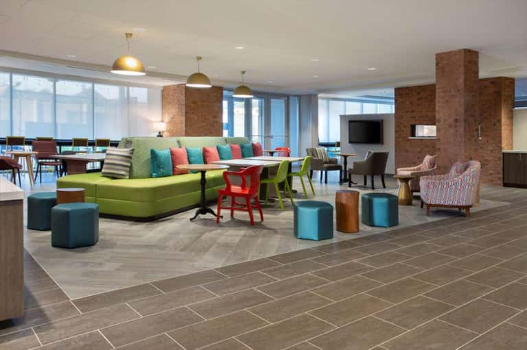 Hotel lobby lounge area with lime green sofa, colorful pillows, and brass pendant lights