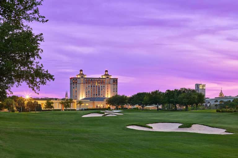 Luxury hotel on golf course at purple sunset with illuminated grounds
