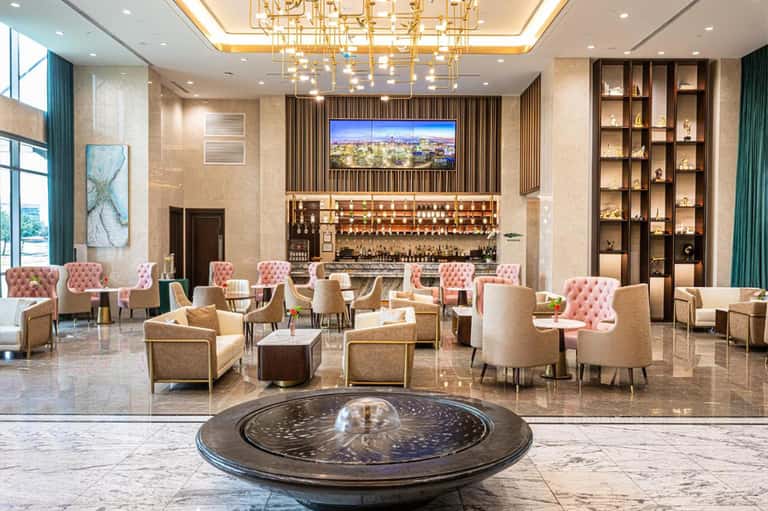 Luxury hotel lobby with bar, fireplace, chandelier, and elegant seating