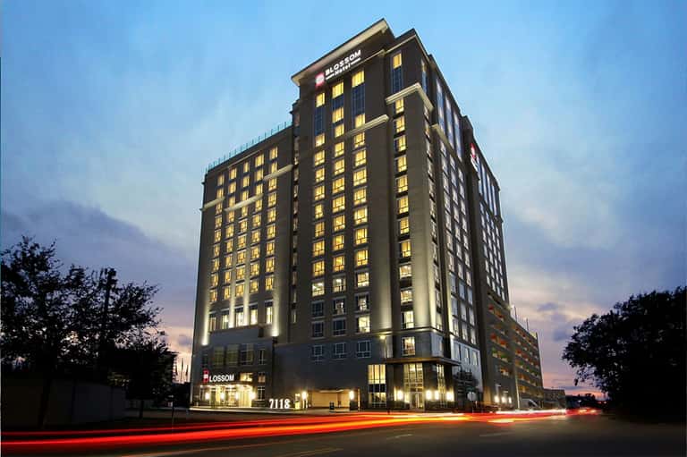 Tall illuminated hotel building at dusk with golden-lit windows and ground-floor storefront entrance
