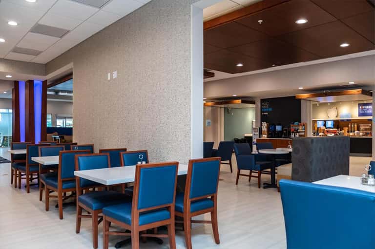 Modern hotel dining area with blue upholstered chairs, wooden frames, and contemporary decor