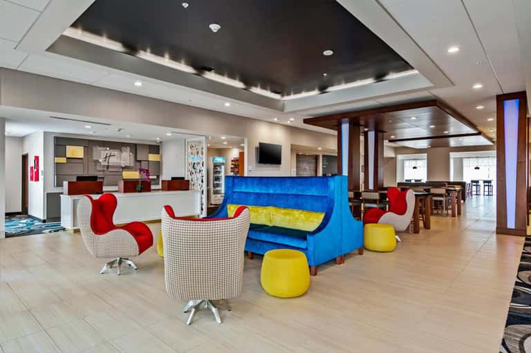 Modern hotel lobby with colorful blue sofa, red chairs, and contemporary reception desk