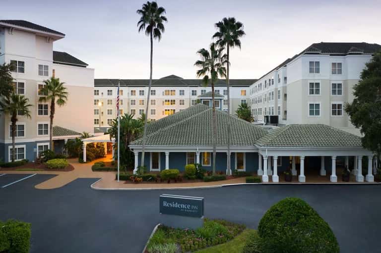 Residence Inn hotel exterior with palm trees, white colonial-style buildings, and covered portico entrance at dusk