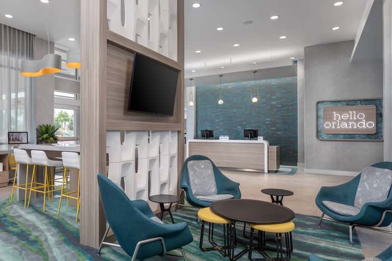 Contemporary hotel lobby featuring teal accent wall, reception desk, and lounge seating area