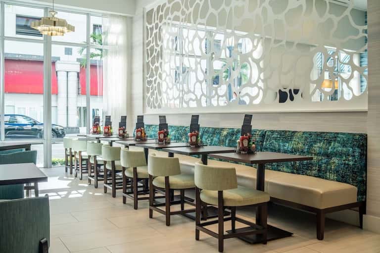 Modern dining area with geometric wall art, turquoise banquette seating, and natural light