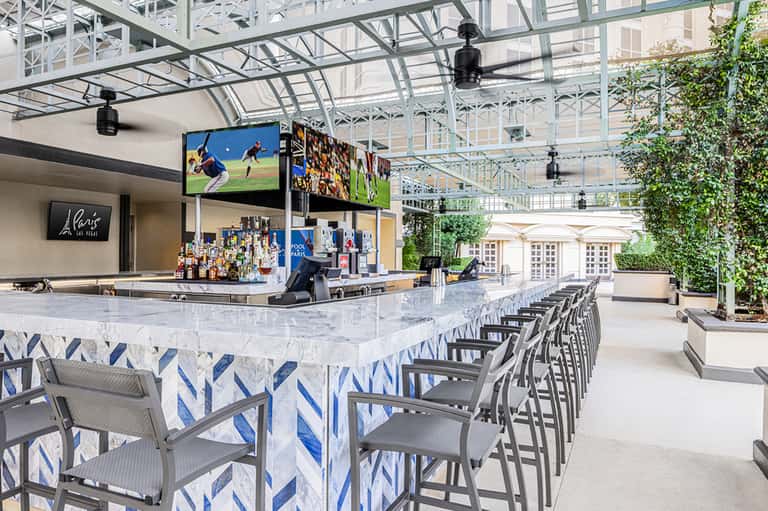 Modern outdoor bar with white marble counter, blue and white décor, and glass ceiling