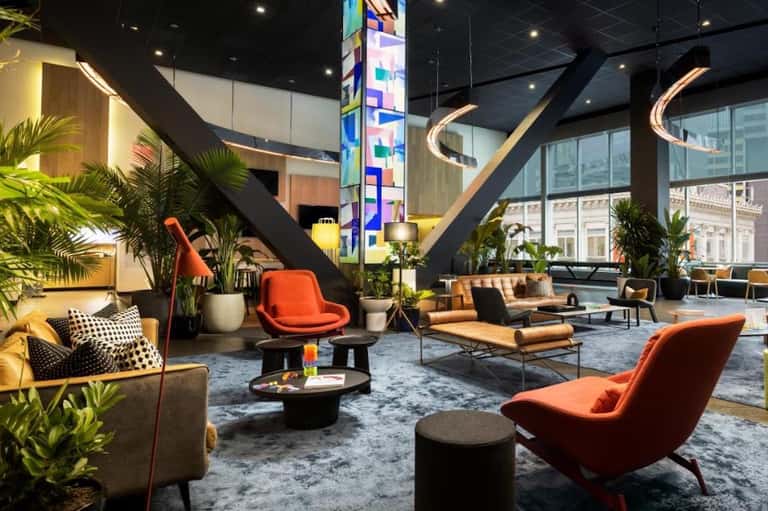 Contemporary hotel lobby with modern furniture, colorful artwork, plants, and curved ceiling details