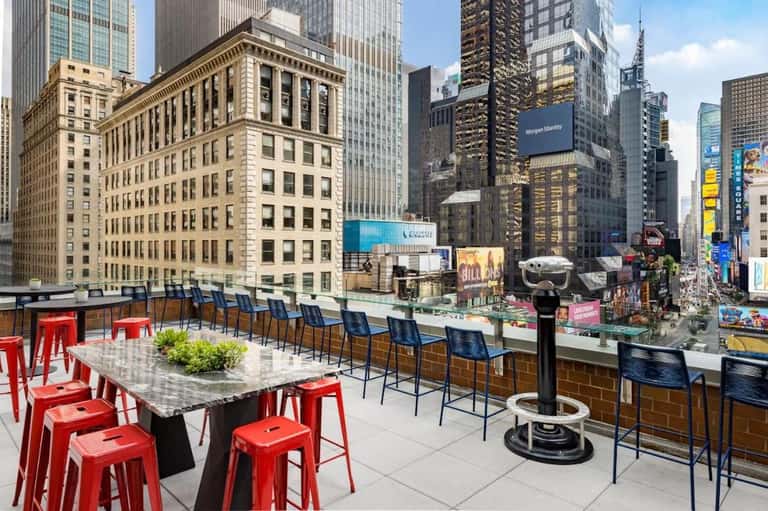 Rooftop bar and lounge with red seating overlooking Times Square in New York City