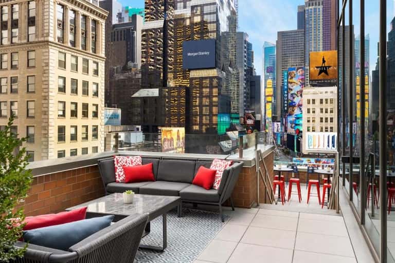 Urban rooftop terrace overlooking Times Square with lounge seating and skyline views