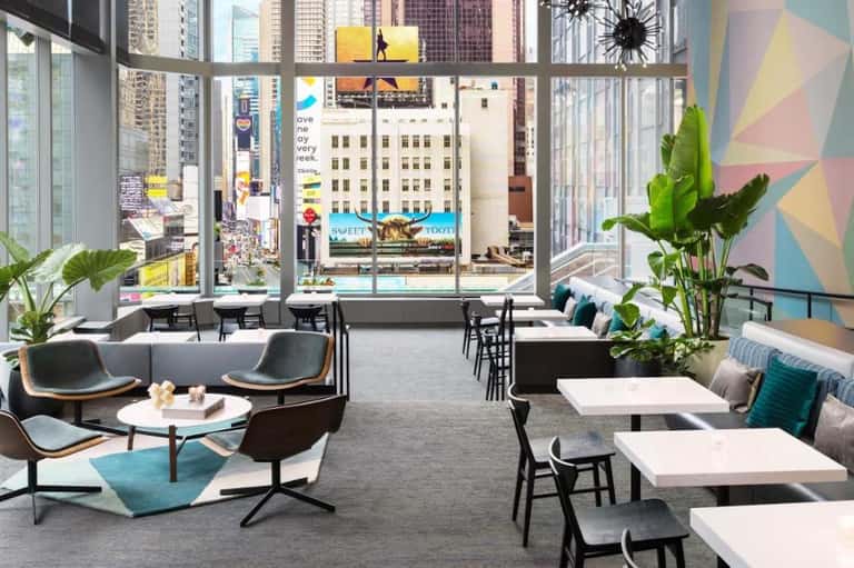 Contemporary lounge with floor-to-ceiling windows overlooking a busy downtown cityscape