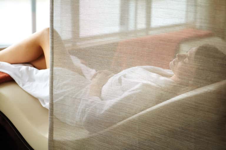 Person relaxing on beige sofa by window with soft natural light