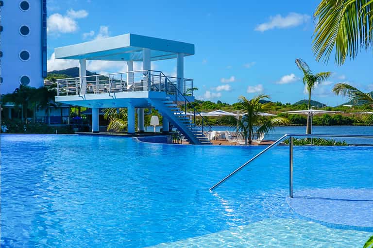 Resort pool with diving platform, palm trees, and tropical waterfront landscape