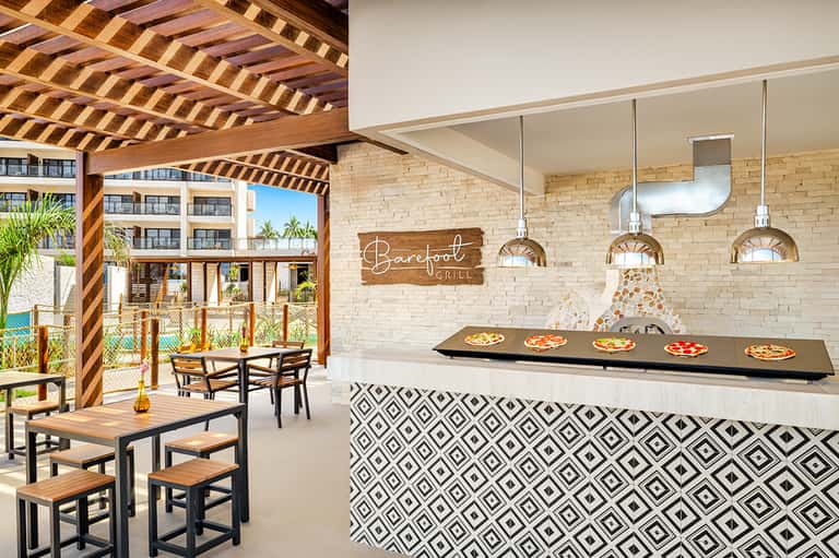Barefoot Grill restaurant with brick oven, wooden pergola seating area, and coastal view