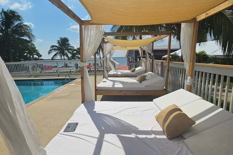 Shaded daybed with ocean view, draped fabric canopy, and adjacent swimming pool
