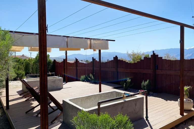 Desert backyard patio with pergola, fire pit, shade sails, and mountain landscape views