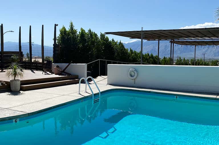 Resort pool with mountain views, shade structures, and lounge seating areas