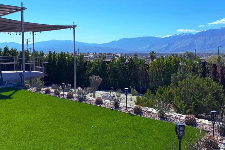 Modern pergola deck with mountain views, landscaping, and manicured lawn