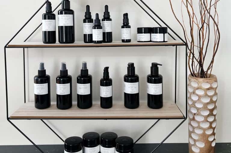 Shelving unit displaying black bottles of skincare serums and creams with white labels