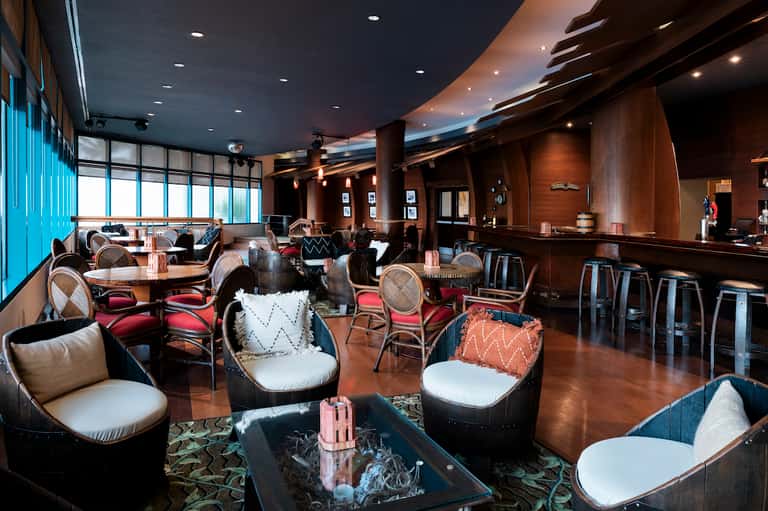 Upscale lounge bar with dark wood finishes, leather seating, and modern lighting
