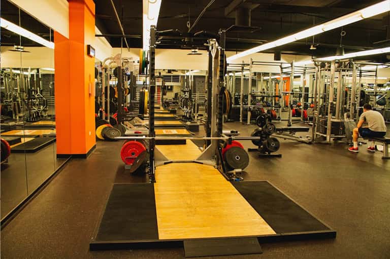 Modern gym interior with weightlifting equipment, barbells, and mirrored walls