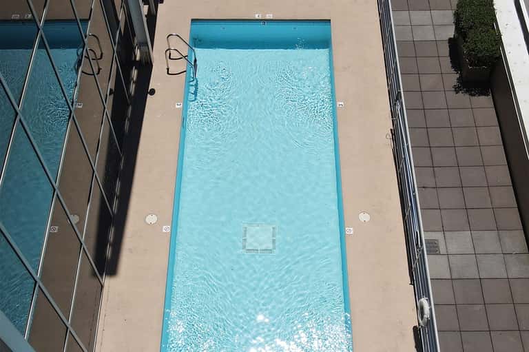 Aerial view of rectangular swimming pool with concrete deck and lounge chairs surrounding it