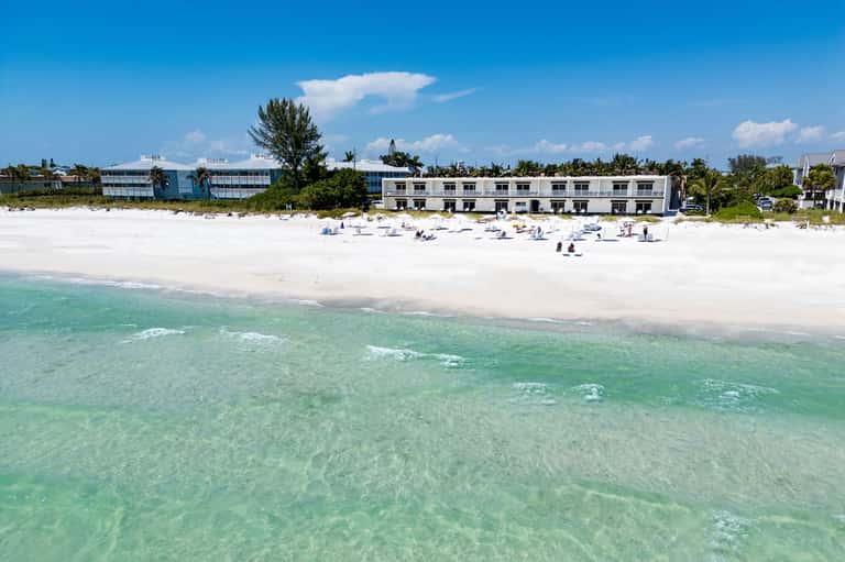 Beachfront resort building with white architecture on pristine sandy beach and turquoise water